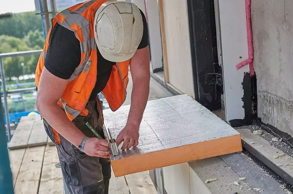 Construction worker cutting insulation to size