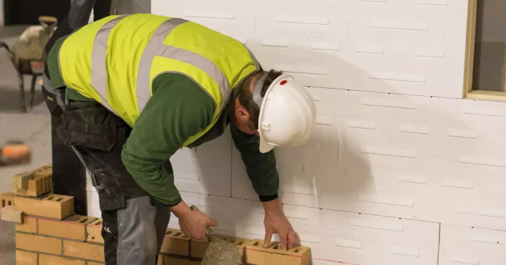 Unilin Insulation image of consruction worker building a wall around cavity therm insulation board